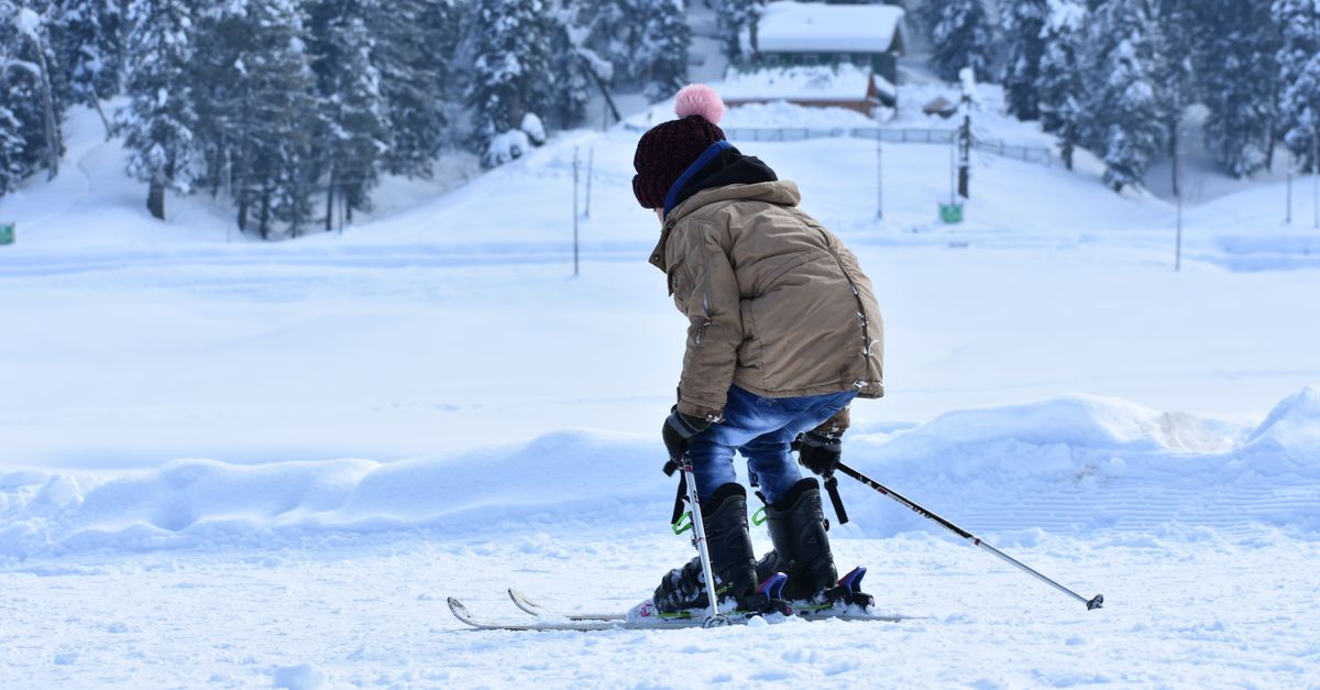 A child in a brown jacket skiing in a snowy landscape, capturing the essence of winter sports fun.